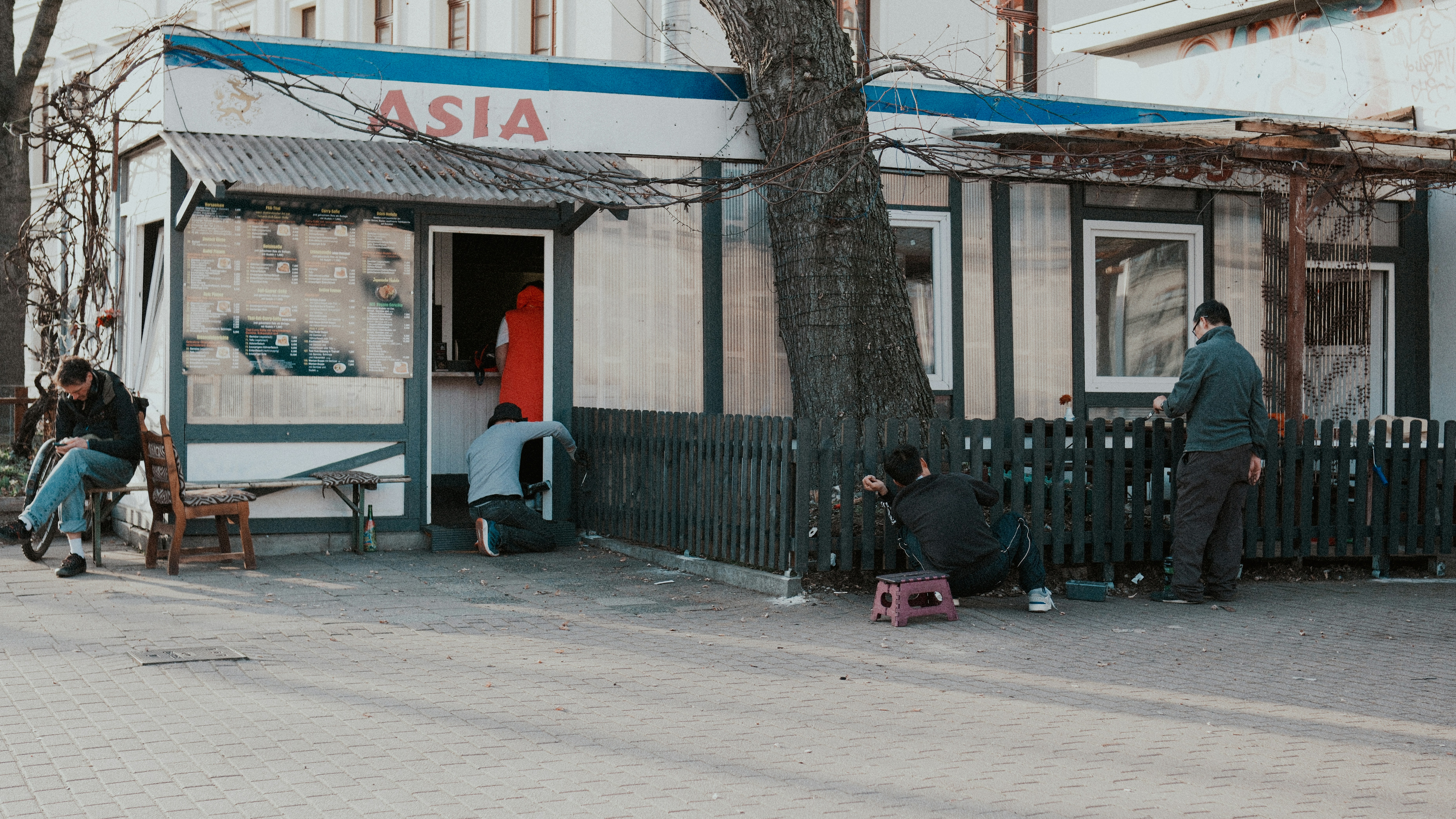 People gathered outside a small asian restaurant building
